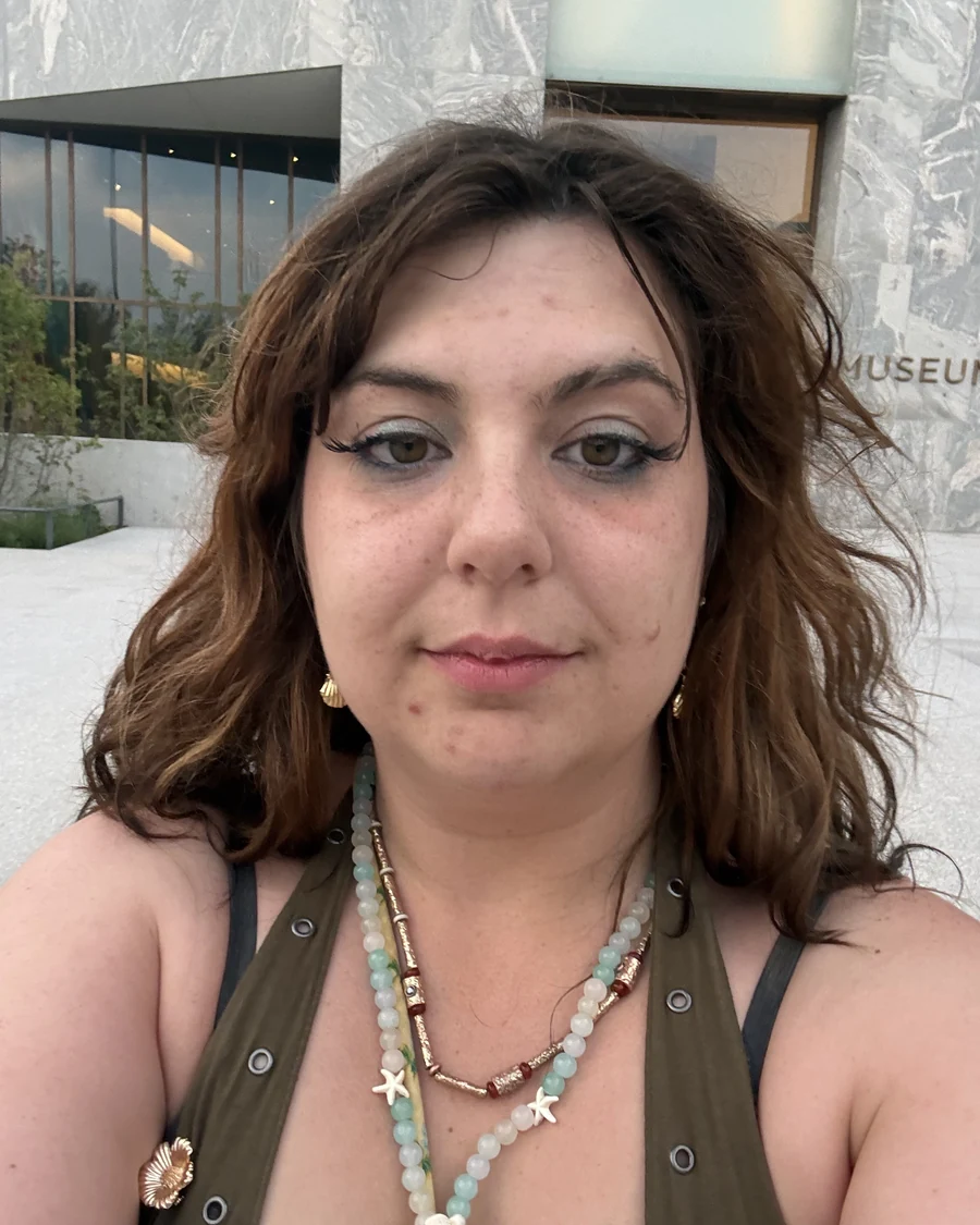 Miranda Sita, founder of Bainbridge Death Support, looking straight into the camera outside a museum in late summer light.