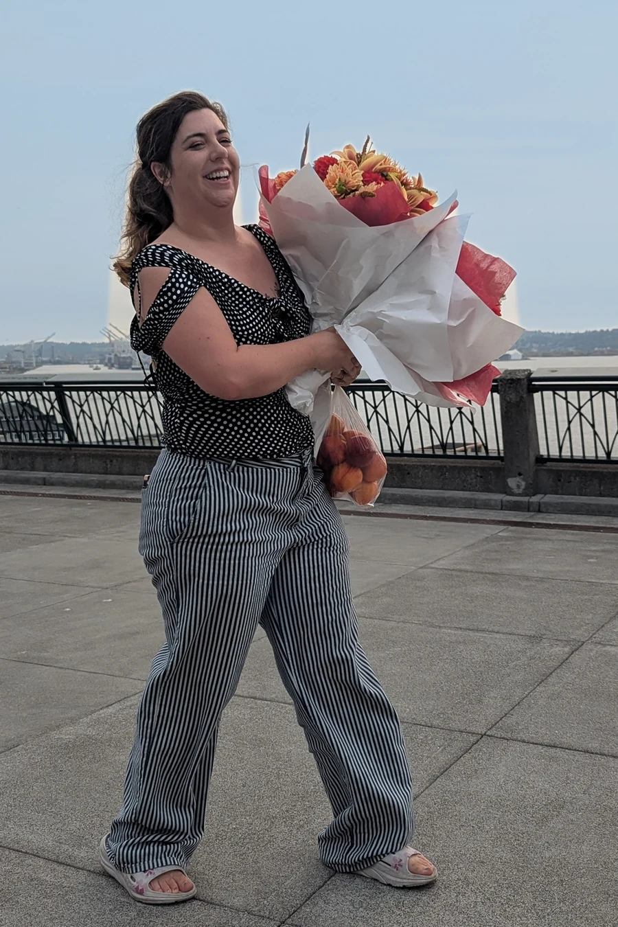 Miranda Sita walking the Seattle waterfront, laughing, an armful of dahlias against her shoulder.